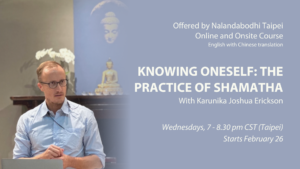 We see Karunika Joshua Erickson in a light-blue blouse and teaching posture with a Buddha Statue and Nalandabodhi's Gandhara Buddha image on the background.